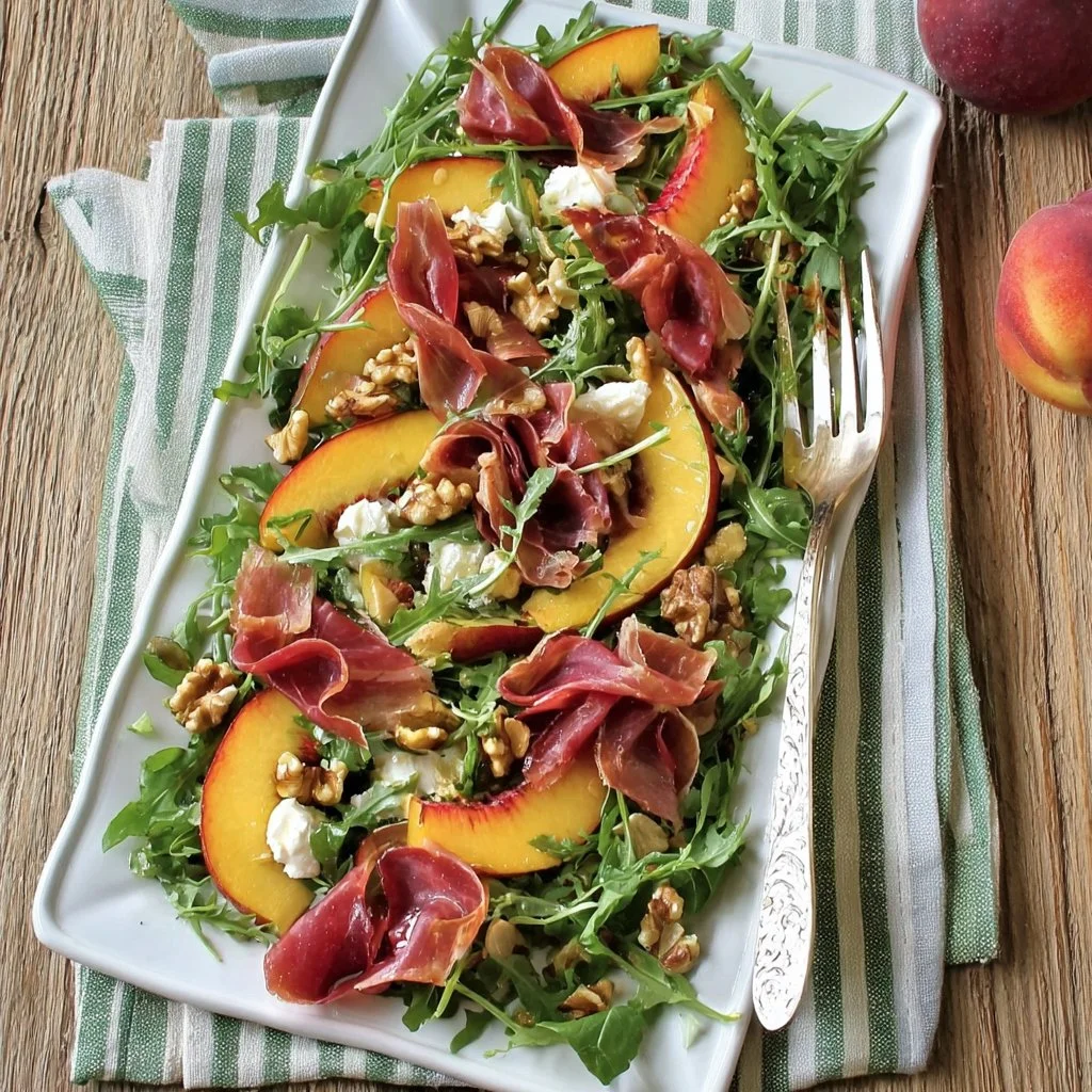 Insalata di pesche, rucola e bresaola servita in un piatto elegante.