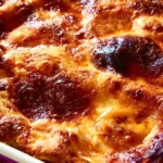 Melanzane alla Parmigiana servite in una teglia, accompagnate da basilico fresco.