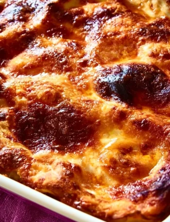 Melanzane alla Parmigiana servite in una teglia, accompagnate da basilico fresco.