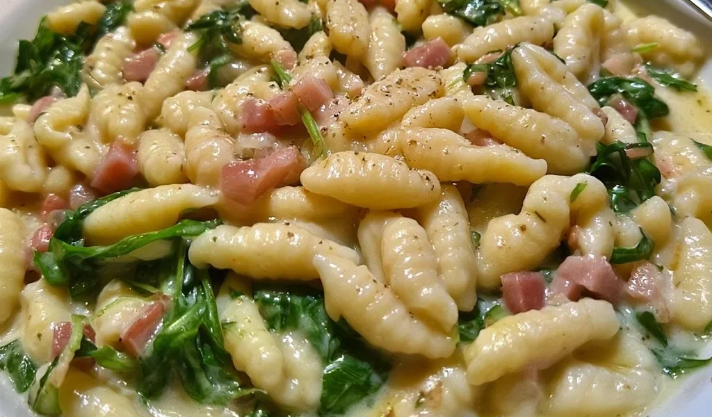 Cavatelli con speck, rucola e crema di patate, piatto gustoso e appetitoso.