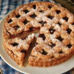 A slice of Linzer Torte topped with powdered sugar, almond crust, and jam filling.