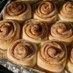 Pane e rotoli alla cannella appena sfornati in una teglia dorata