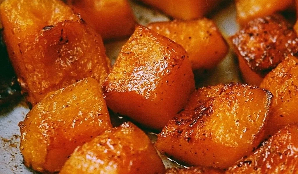 Bowl of roasted pumpkin garnished with herbs and spices