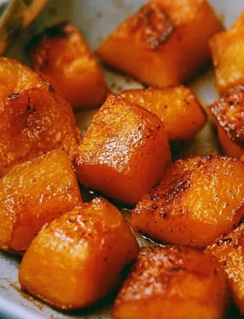 Bowl of roasted pumpkin garnished with herbs and spices