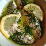 Sgombro cucinato con olio, limone e prezzemolo, servito su un piatto elegante.