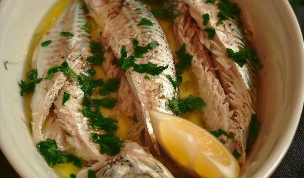 Sgombro lesso con olio e limone servito in un piatto elegante.