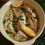 Sgombro lesso con olio e limone servito in un piatto elegante.