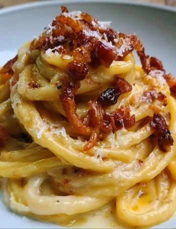 Spaghettoni con crema di patate, pecorino e guanciale serviti in un piatto elegante.