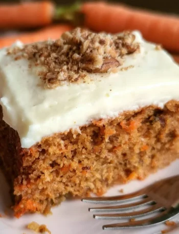 Fetta di Torta di Carote Sana servita su un piatto con decorazioni naturali.