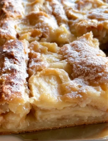 Fetta di Torta di Mele appena sfornata con mele fresche e cannella.