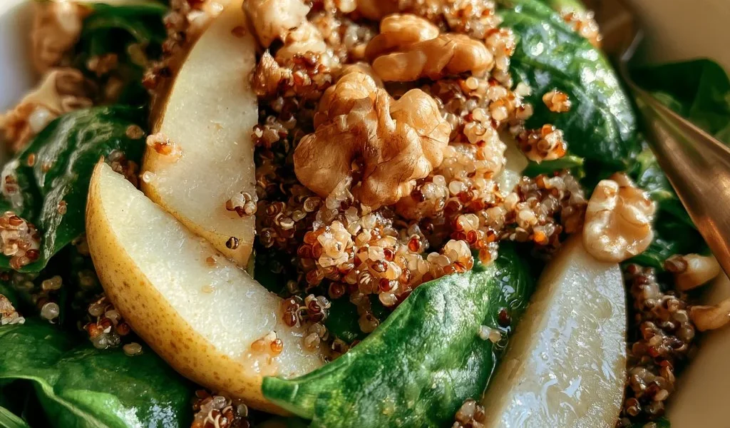 Insalata di quinoa con pere, spinaci e noci in un piatto colorato e salutare