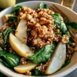 Insalata di quinoa con pere, spinaci e noci in un piatto colorato e salutare