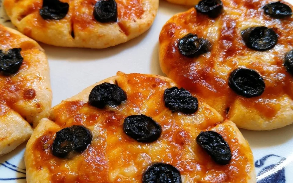 Pizzette ragno con olive nere, un finger food italiano appetitoso