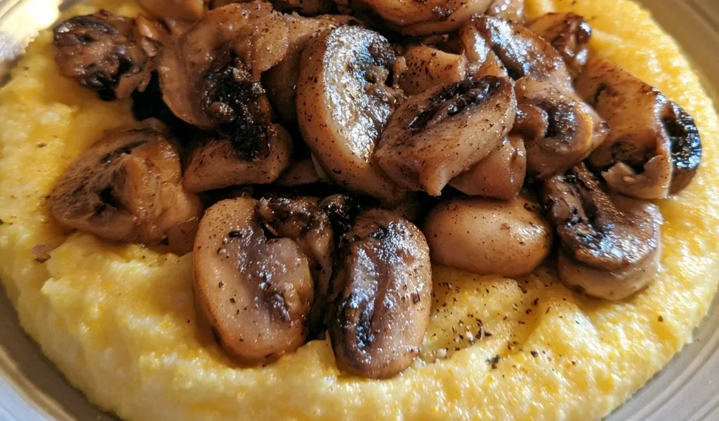 Polenta morbida con funghi trifolati su un piatto
