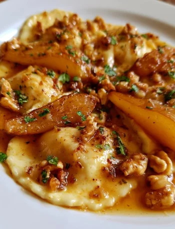 Ravioli di ricotta con salsa di noci e pere serviti su un piatto elegante