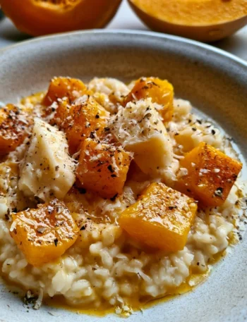 Piatto di risotto alla zucca e Taleggio con decorazioni di erbe fresche