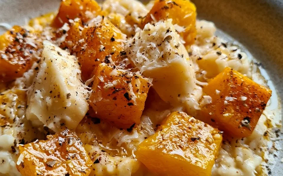 Piatto di risotto alla zucca e Taleggio con decorazioni di erbe fresche