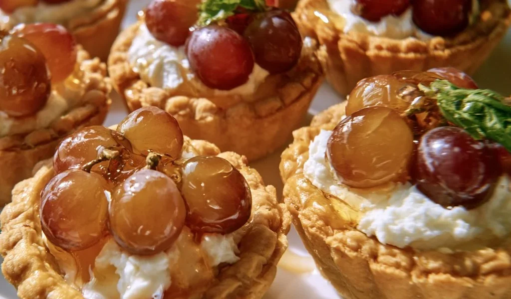 Tartellette con uva, caprino e miele su un piatto elegante