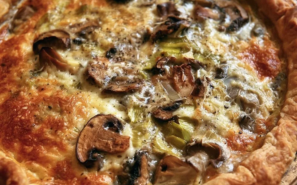 Torta salata con funghi, porri e fontina pronta da servire.